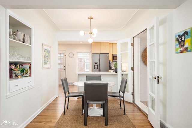 dining area featuring light wood-type flooring, a chandelier, and baseboards