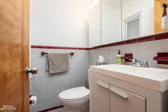 half bath featuring tile walls, toilet, and vanity