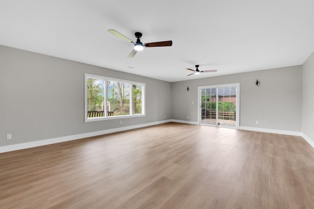 unfurnished room with ceiling fan, plenty of natural light, light wood finished floors, and baseboards