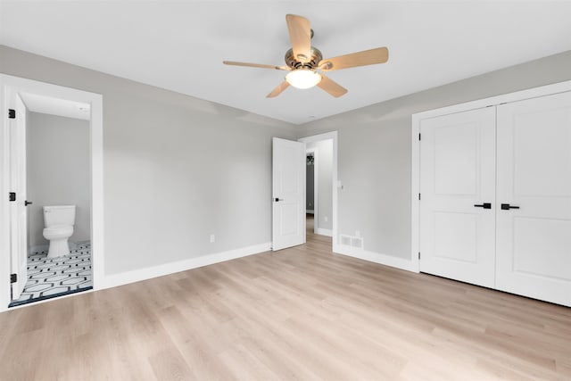 unfurnished bedroom featuring baseboards, light wood-type flooring, a closet, connected bathroom, and a ceiling fan