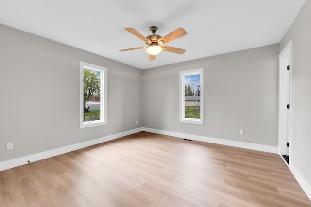 unfurnished room featuring light wood-type flooring, a ceiling fan, and baseboards