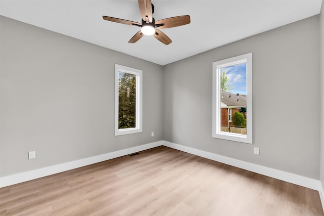 spare room featuring plenty of natural light, wood finished floors, and baseboards
