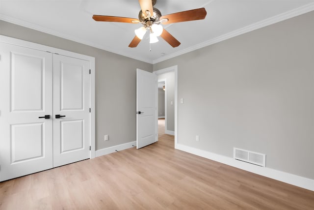 unfurnished bedroom featuring light wood-style flooring, baseboards, crown molding, and a closet