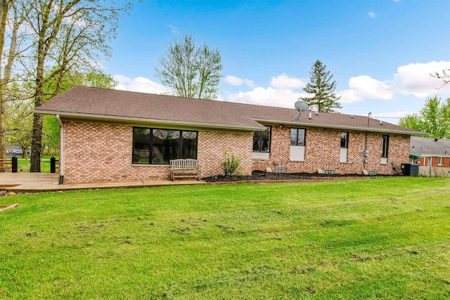 back of house featuring cooling unit, brick siding, a yard, and a shingled roof