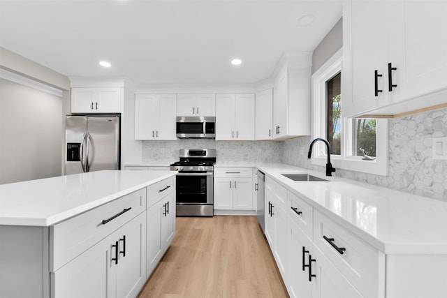 kitchen with appliances with stainless steel finishes, a sink, light wood-type flooring, decorative backsplash, and recessed lighting