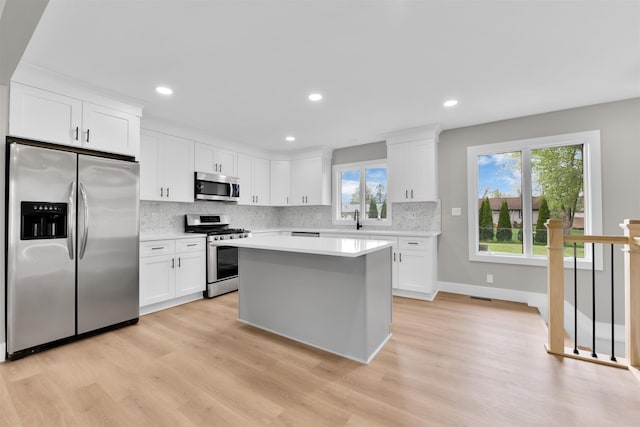 kitchen with appliances with stainless steel finishes, light countertops, backsplash, white cabinetry, and recessed lighting