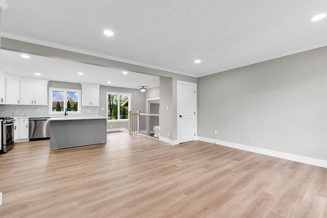 unfurnished living room with ornamental molding, recessed lighting, baseboards, light wood-style floors, and a sink