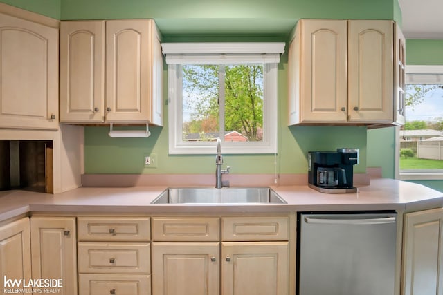 kitchen with stainless steel dishwasher, a sink, and light countertops
