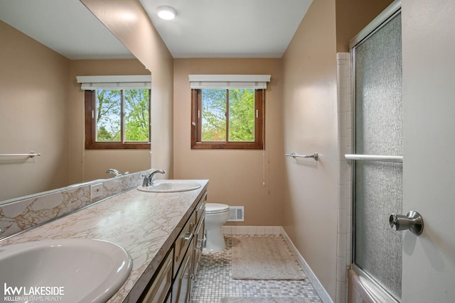 bathroom with toilet, double vanity, an enclosed shower, and baseboards
