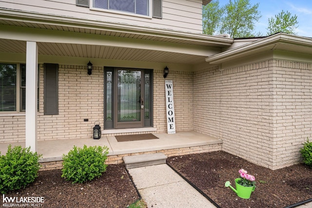 entrance to property featuring covered porch and brick siding