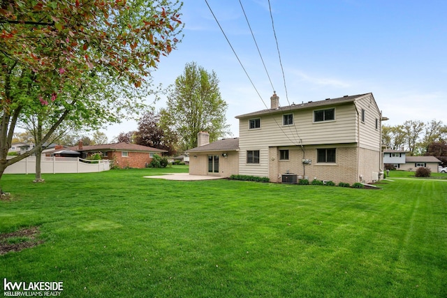 rear view of house with a chimney, brick siding, central air condition unit, and a patio