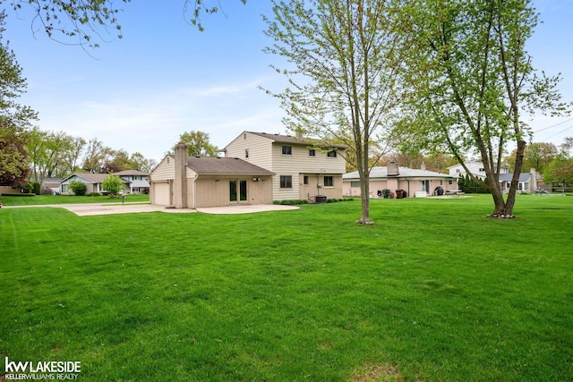 rear view of house with a chimney, a lawn, concrete driveway, brick siding, and an attached garage