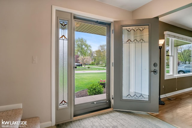 doorway to outside featuring healthy amount of natural light, baseboards, and wood finished floors