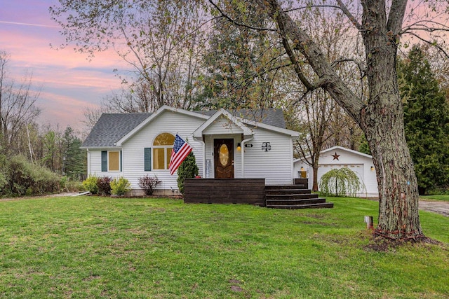 view of front of home with an outdoor structure, a yard, a detached garage, and a shingled roof