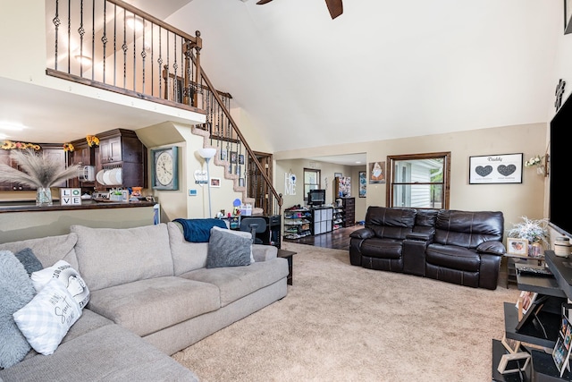 carpeted living area with high vaulted ceiling, stairs, and a ceiling fan