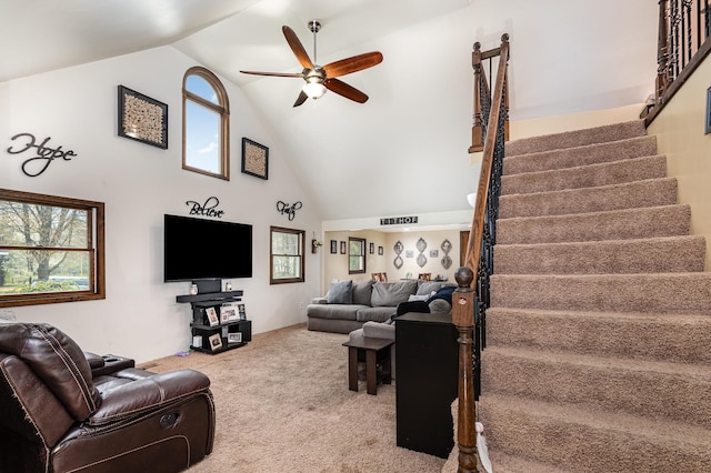 carpeted living room with ceiling fan, stairway, and high vaulted ceiling
