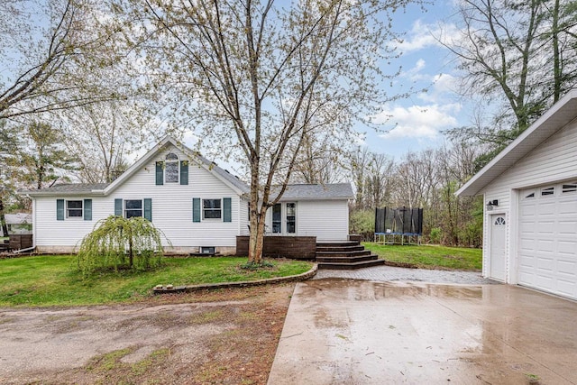 view of front of house with a trampoline, concrete driveway, a front yard, and a garage