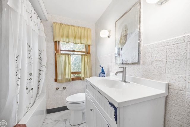 bathroom with tile walls, toilet, vanity, shower / bath combo with shower curtain, and a wainscoted wall