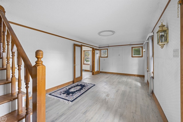 entryway with light wood finished floors, baseboards, wallpapered walls, stairway, and french doors
