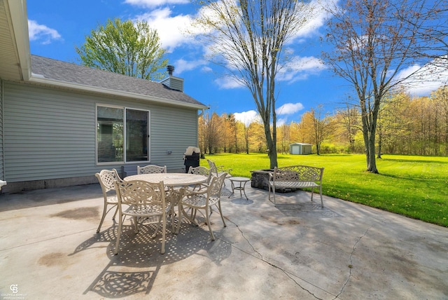 view of patio with outdoor dining space, a storage shed, and an outbuilding