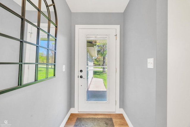 doorway to outside with wood finished floors, plenty of natural light, and baseboards