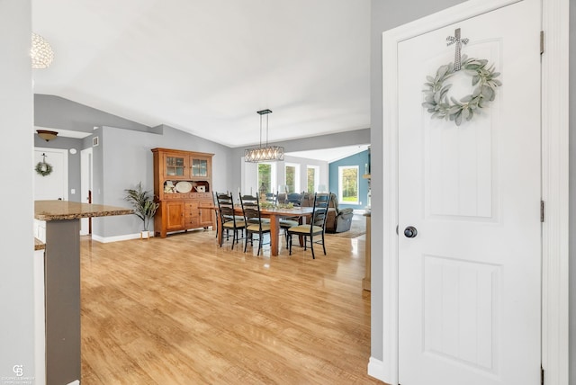 dining area featuring vaulted ceiling, light wood-style flooring, baseboards, and a chandelier