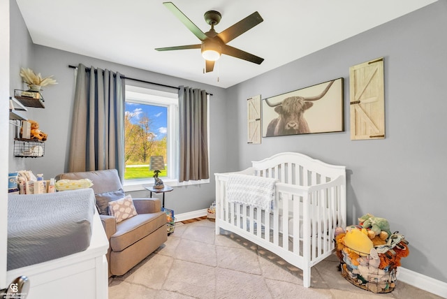 bedroom with a crib, baseboards, and ceiling fan