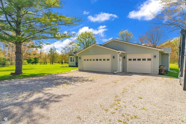 view of front of home with gravel driveway, a front lawn, and an attached garage