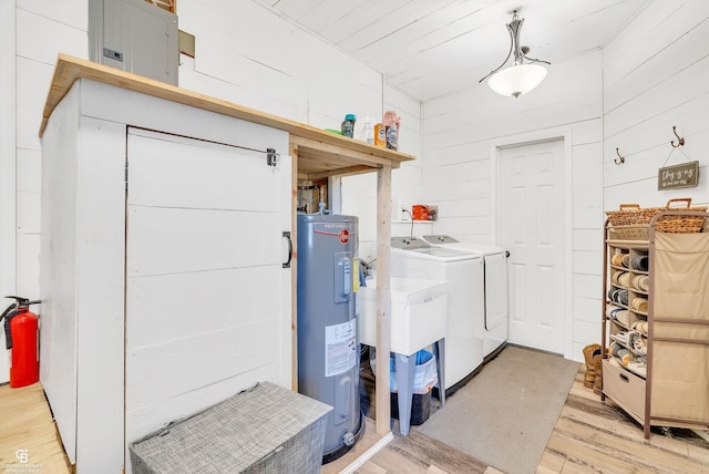 laundry area with washing machine and dryer, water heater, light wood-style floors, and wood walls