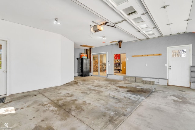 garage featuring freestanding refrigerator and a garage door opener