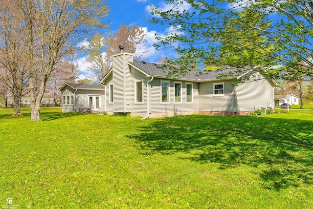back of house with a chimney, a lawn, and french doors