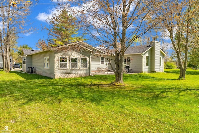 back of property with a yard, a patio area, and a chimney