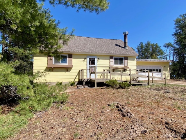 view of front facade with a deck, an attached garage, and a shingled roof