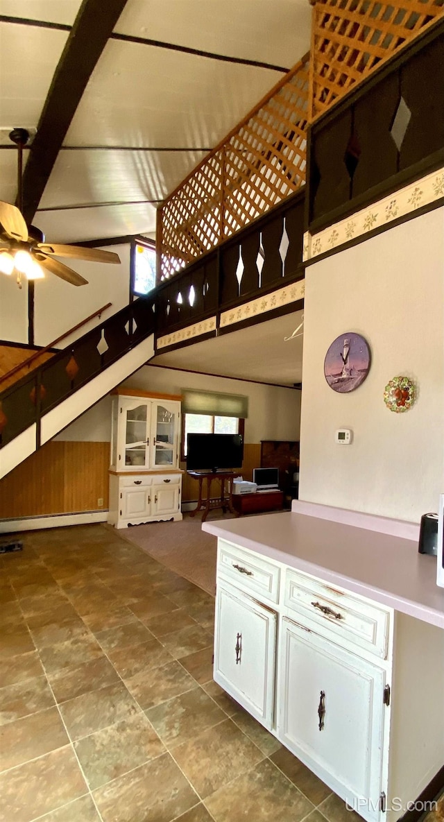 interior space featuring white cabinets, ceiling fan, and a high ceiling