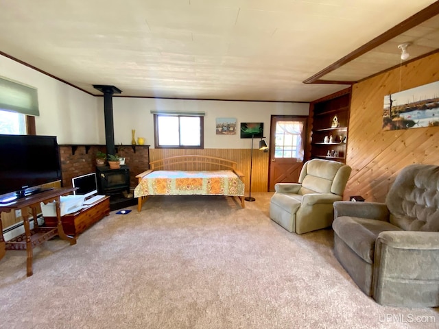 bedroom with wooden walls, carpet, a wood stove, a wainscoted wall, and ornamental molding