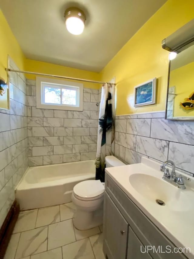 bathroom with tile walls, toilet, shower / tub combo, vanity, and a wainscoted wall