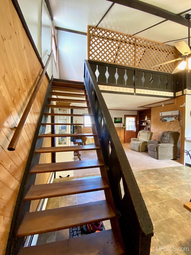 stairway featuring wood walls and a ceiling fan