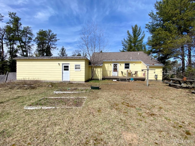 back of house featuring a wooden deck and a garden