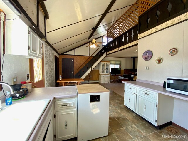 kitchen featuring a peninsula, a sink, white cabinetry, ceiling fan, and lofted ceiling