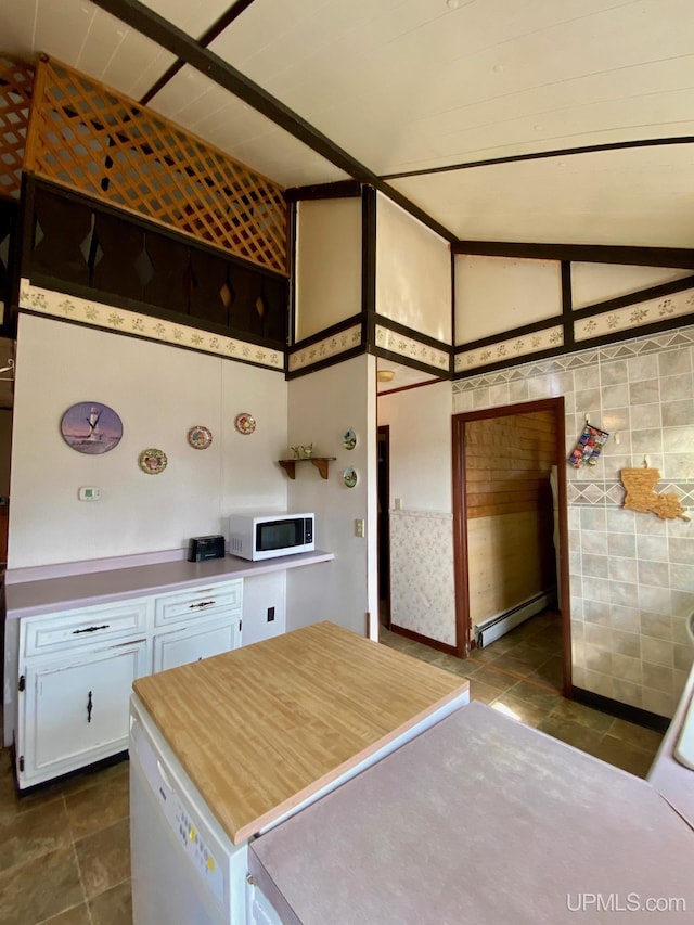 kitchen with white microwave, a baseboard radiator, white cabinetry, dark tile patterned floors, and light countertops