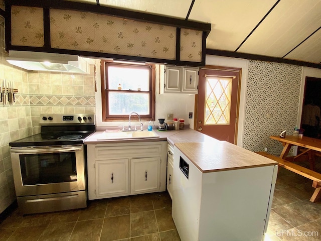 kitchen with stainless steel range with electric cooktop, a sink, under cabinet range hood, a peninsula, and light countertops