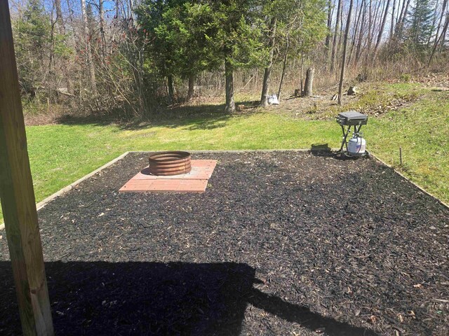 view of green lawn with an outdoor fire pit