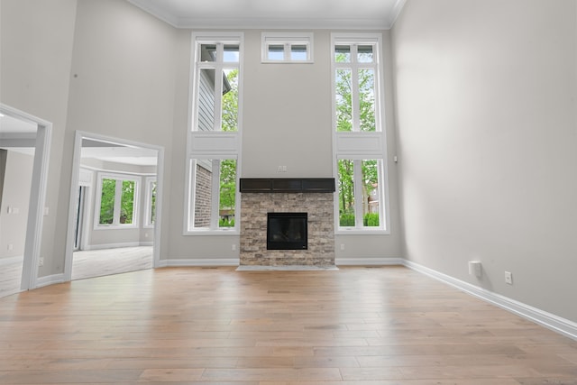 835 Crestwood Ln, Rochester Hills, MI 48309 - unfurnished living room featuring ornamental molding, a towering ceiling, light wood finished floors, plenty of natural light, and a stone fireplace