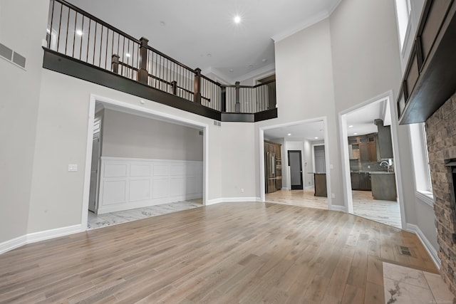 835 Crestwood Ln, Rochester Hills, MI 48309 - unfurnished living room with light wood-type flooring, a high ceiling, a stone fireplace, crown molding, and baseboards