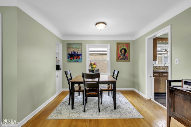 dining area with plenty of natural light, light wood-type flooring, baseboards, and built in shelves