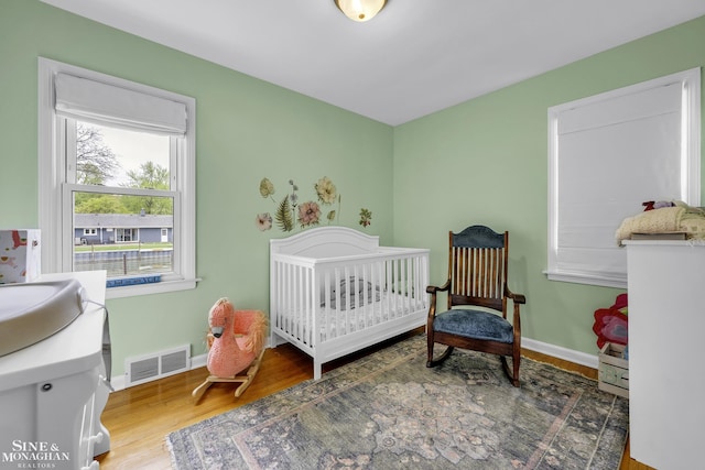 bedroom featuring wood finished floors, baseboards, and a crib