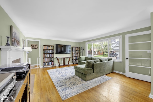 living area with light wood finished floors, a fireplace, baseboards, and built in features