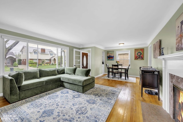 living room featuring a premium fireplace, light wood-type flooring, and baseboards