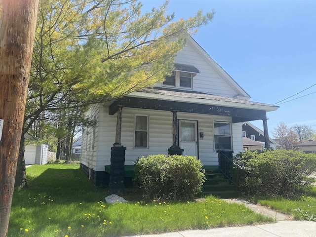 view of front of home with a porch, an outdoor structure, and a front yard