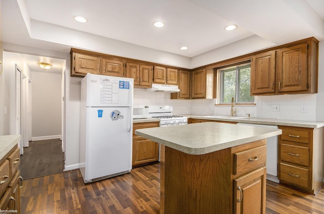 kitchen featuring white appliances, under cabinet range hood, a sink, dark wood-style flooring, and recessed lighting